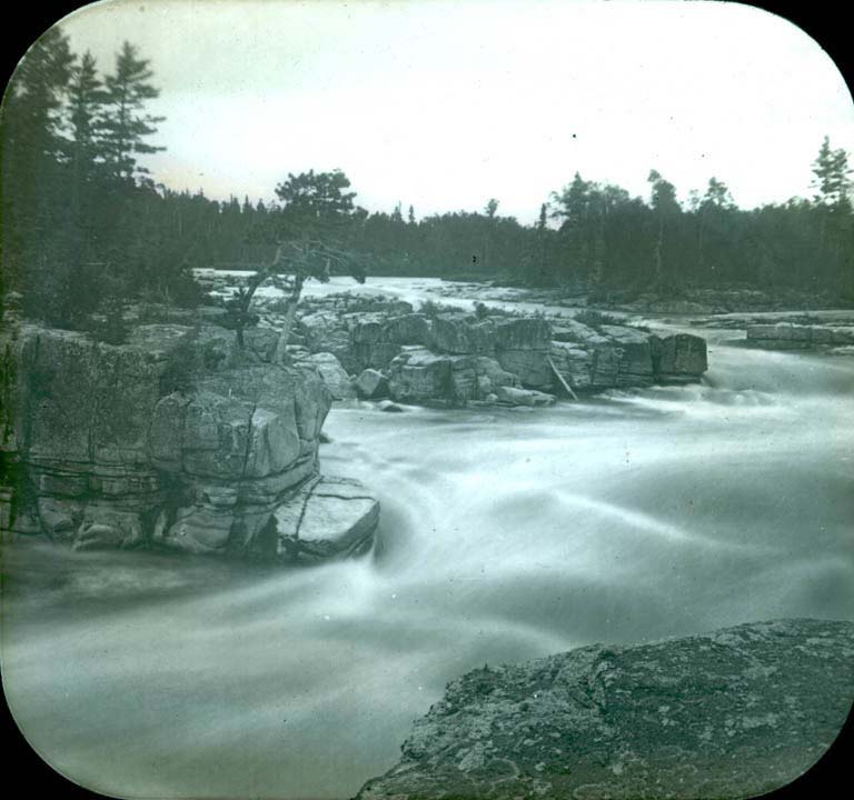 Black and white image of river passing through rocky cliffs and ledges
