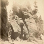 Black and white photograph of tall rock formations and people on beach