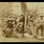 Photographie noir et blanc de cinq femmes et trois hommes devant un arbre